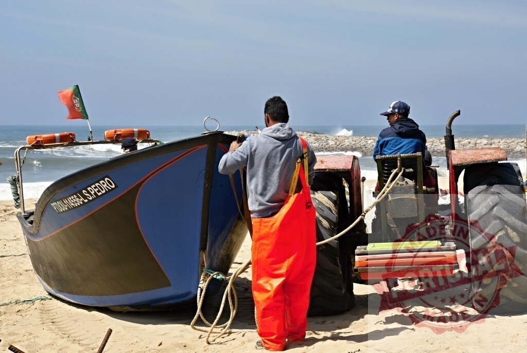 Fishermen pulling boat onto Portugal beach | Fishermen using a tractor to retrieve a traditional fishing boat from the ocean onto the sand - Realisiert mit Pictrs.com