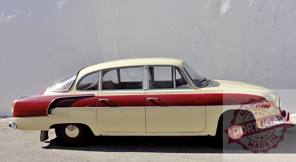Red and beige Tatra 603 parked near white wall | Side view of vintage Tatra 603 automobile parked near a white wall, showcasing its classic design - Realized with Pictrs.com