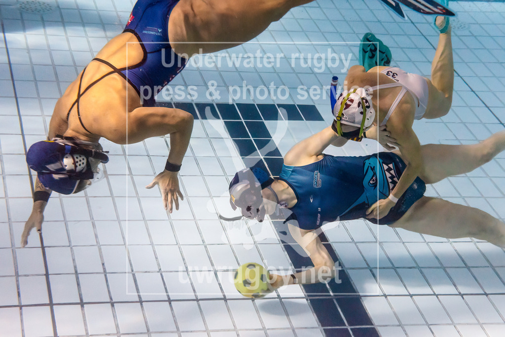 24. - 26.11.2023: Unterwasser-Rugby Champions Cup 2023  | Damen-Spiel um Platz 5:  Amager Uv-Rugby (Dänemark) in blau gegen UWRC Wien / Österreich in weiß. Anna Kjelstrup Frandsen (blau #18) passt zu ihrer Mitspielerin Marianna Heidam (blau #11), Die österreichische Meisterin Nausikaa Decker (weiß #33)versucht sie daran zu hindern. - Realisiert mit Pictrs.com
