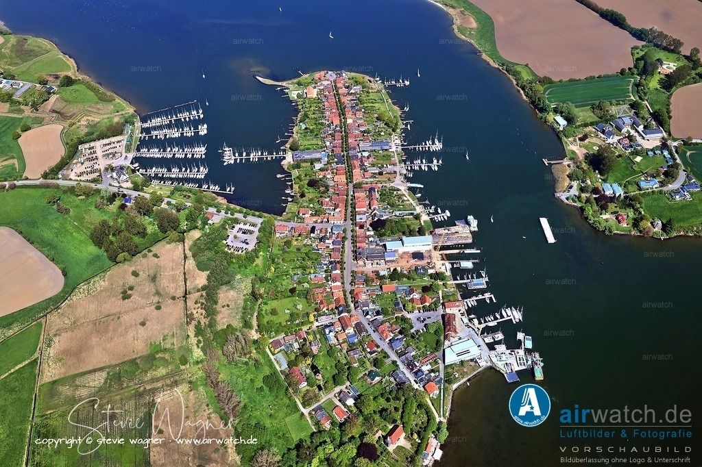 Luftbild Stadt Arnis - ein Ort mit besonderem maritimen Ambiente | Die Lange Straße zieht sich durch die gesamte Stadt und ist der zentrale Spazierweg. Zahlreiche Häuser sind noch im Originalzustand mit Utluchten, und die Stockrosen an den Hauswänden verleihen dem Ort einen märchenhaften Charme. Hier finden sich auch kleine Cafés wie das beliebte „Schleiperle“, in dem man regionalen Kuchen genießen kann.