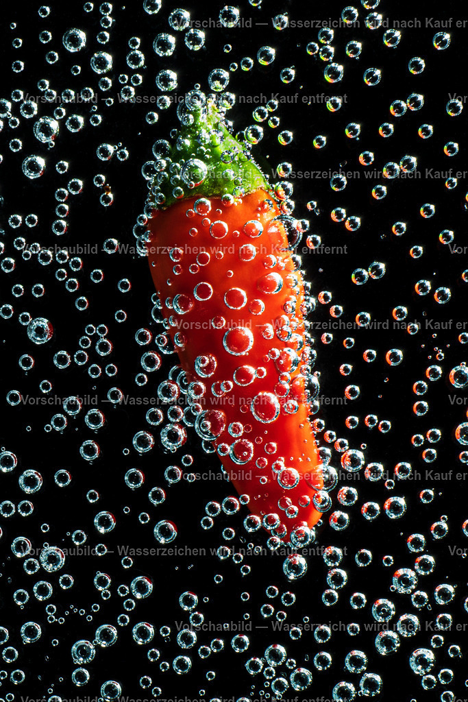 rote Peperonie vor schwartzen Hintergrund in einen Meer aus Luftblasen | rote Peperonie vor schwartzen Hintergrund in einen Meer aus sprudeligen Luftblasen. - Realisiert mit Pictrs.com