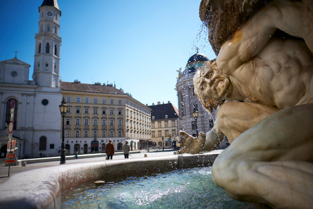 Brunnen Macht zu Lande | Wien, Austria - April 07, 2020: Fotografische Eindrücke auf dem Weg von Floridsdorf zum Stephansplatz während der Corona-Krise; Brunnen Macht zu Lande, im Hintergrund die Michaelerkirche. - Realisiert mit Pictrs.com