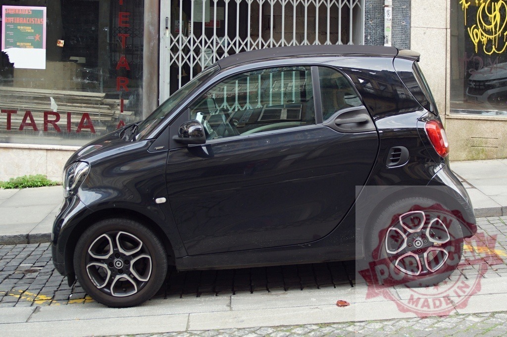 Black Smart Fortwo microcar parked on urban street | Black Smart Fortwo car parked on a cobblestone street by a building - Realisiert mit Pictrs.com