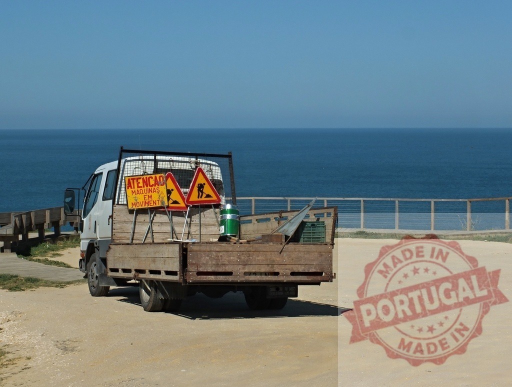 Work truck with construction signs on coastal road in Portugal | Work truck carrying construction signs parked by the ocean under a clear blue sky - Realisiert mit Pictrs.com