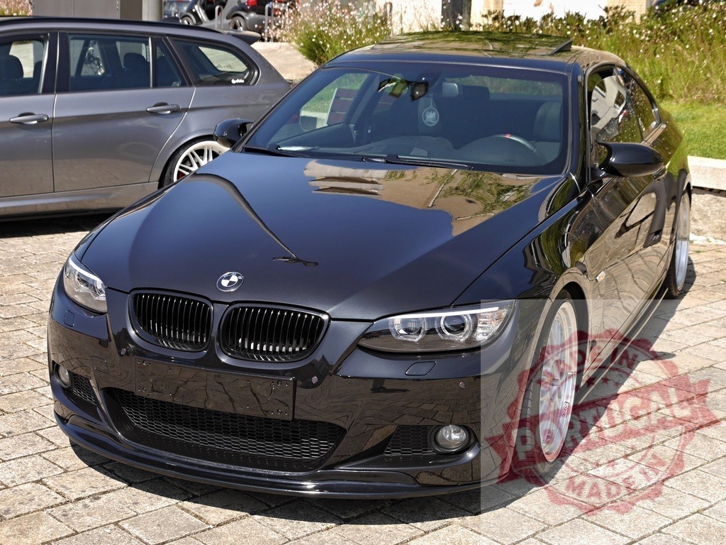Black BMW E92 coupe parking on street | Reflected light on a black customized BMW coupe parked on a paved street - Realized with Pictrs.com