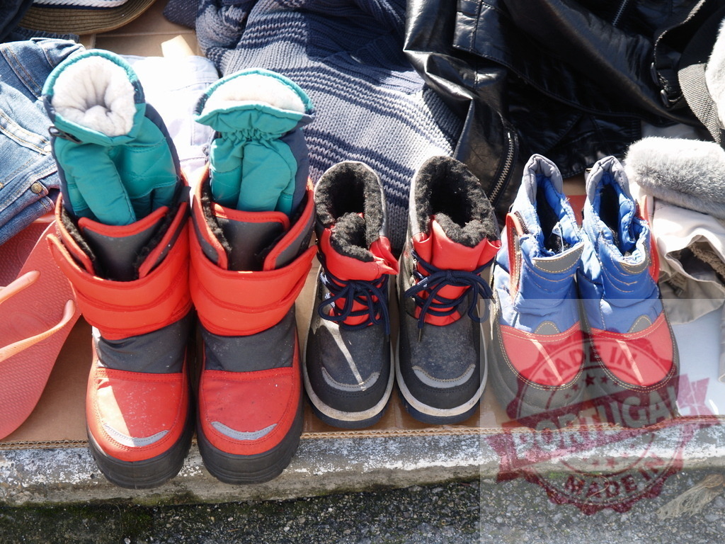 Children's used boots and clothing at flea market | Used colorful children's boots for sale at an outdoor market stall - Realisiert mit Pictrs.com