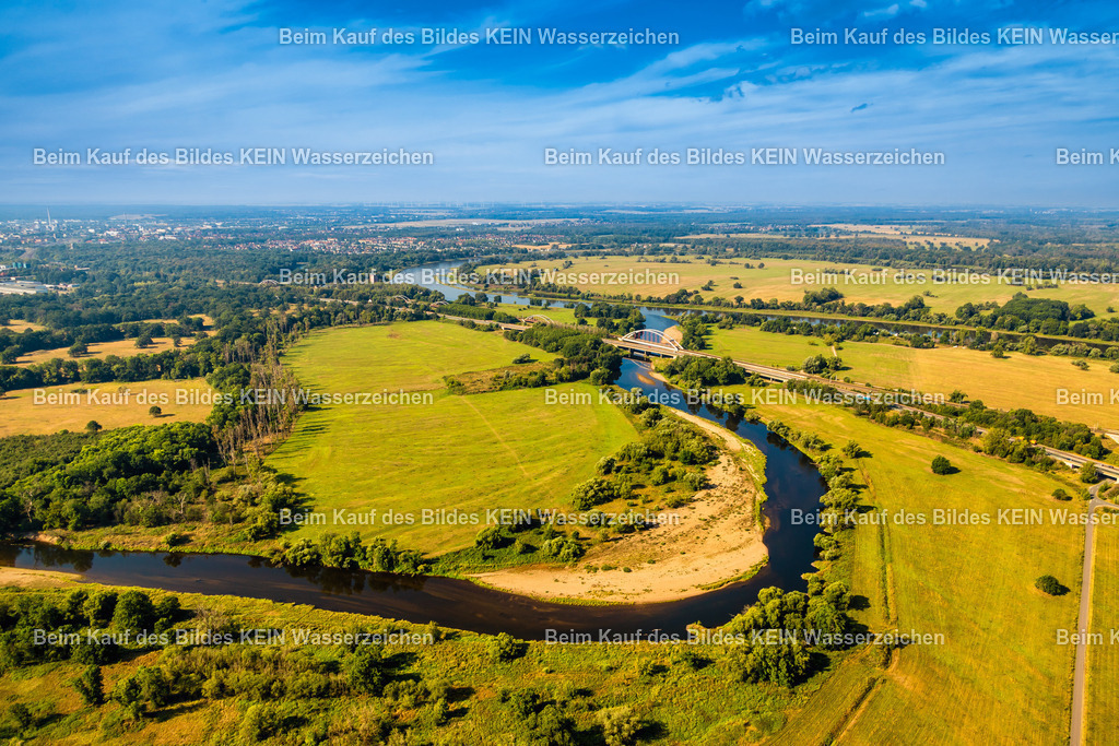 Mulde bei Roßlau | Diese Luftaufnahme zeigt die Mulde bei Roßlau in Sachsen-Anhalt als eindrucksvolles Hauptmotiv einer weitläufigen Flusslandschaft. In sanften Kurven schlängelt sich der Fluss durch die grüne Auenlandschaft und prägt das Bild mit seinem natürlichen Verlauf. Aus der Vogelperspektive werden die Dimensionen des Flusstals und die harmonische Einbettung der Mulde in die umgebende Natur besonders deutlich sichtbar.Die weitläufigen Wiesen, Felder und Uferbereiche verleihen der Landschaft ihren charakteristischen Reiz. Die Mulde gehört zu den bedeutenden Nebenflüssen der Elbe und schafft mit ihren Auen wertvolle Lebensräume für zahlreiche Tier- und Pflanzenarten. Aus der Luft zeigt sich die natürliche Dynamik des Flusses besonders eindrucksvoll.Über der Landschaft spannt sich ein klarer blauer Himmel, der die sommerliche Atmosphäre der Aufnahme unterstreicht. Das Zusammenspiel aus Wasser, sattem Grün und den kräftigen Farben eines sonnigen Tages verleiht dem Bild eine außergewöhnliche Wirkung und erinnert an klassische Postkartenmotive der mitteldeutschen Flusslandschaften.Das Luftbild dokumentiert die Schönheit der Mulde bei Roßlau und zeigt einen der reizvollsten Landschaftsräume Sachsen-Anhalts aus der Vogelperspektive. Die Aufnahme eignet sich hervorragend für touristische Publikationen, regionale Dokumentationen und die Präsentation der vielfältigen Flusslandschaften Mitteldeutschlands. - Realisiert mit Pictrs.com