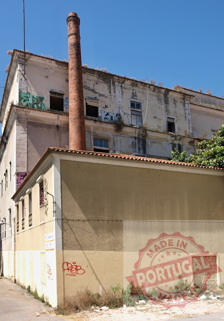 Abandoned industrial building with a tall brick chimney | Neglected factory building featuring an old brick chimney and graffiti under a clear blue sky - Realized with Pictrs.com