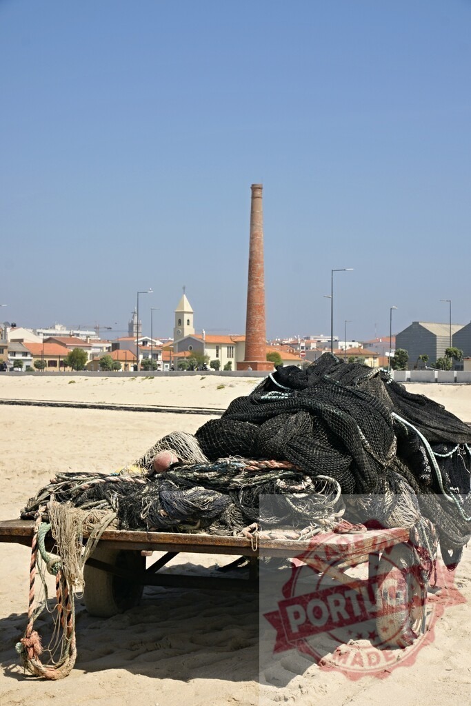 Aveiro Region - Portugal Fishing nets on beach with Povoa do Varzim chimney | Fishing nets resting on a cart on the sandy beach with Povoa de Varzim cityscape - Realisiert mit Pictrs.com