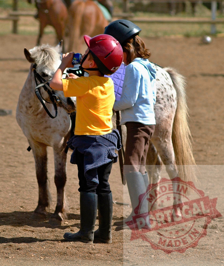 Children drinking water during a pony riding lesson | Young children wearing helmets and boots taking a break from learning equestrian sports - Realisiert mit Pictrs.com