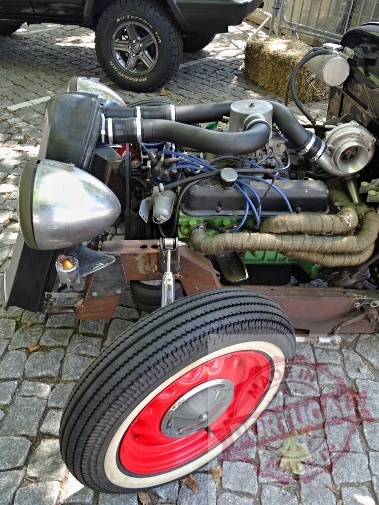 Customized hot rod car showcasing powerful engine and red wheel | Close-up of a customized hot rod car, highlighting its modified engine and red and white wheel - Realized with Pictrs.com