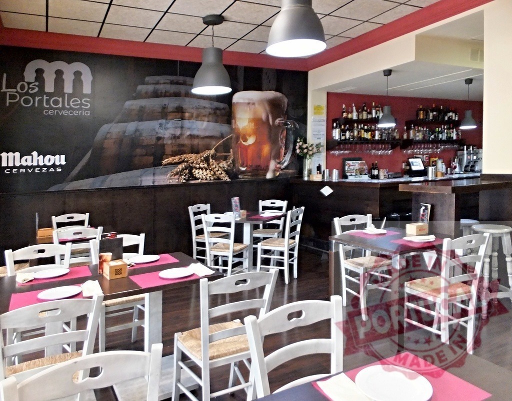 Los Portales cervecería interior with Mahou branding in Madrid | Empty tables and chairs ready for customers in a traditional Spanish bar and restaurant - Realisiert mit Pictrs.com