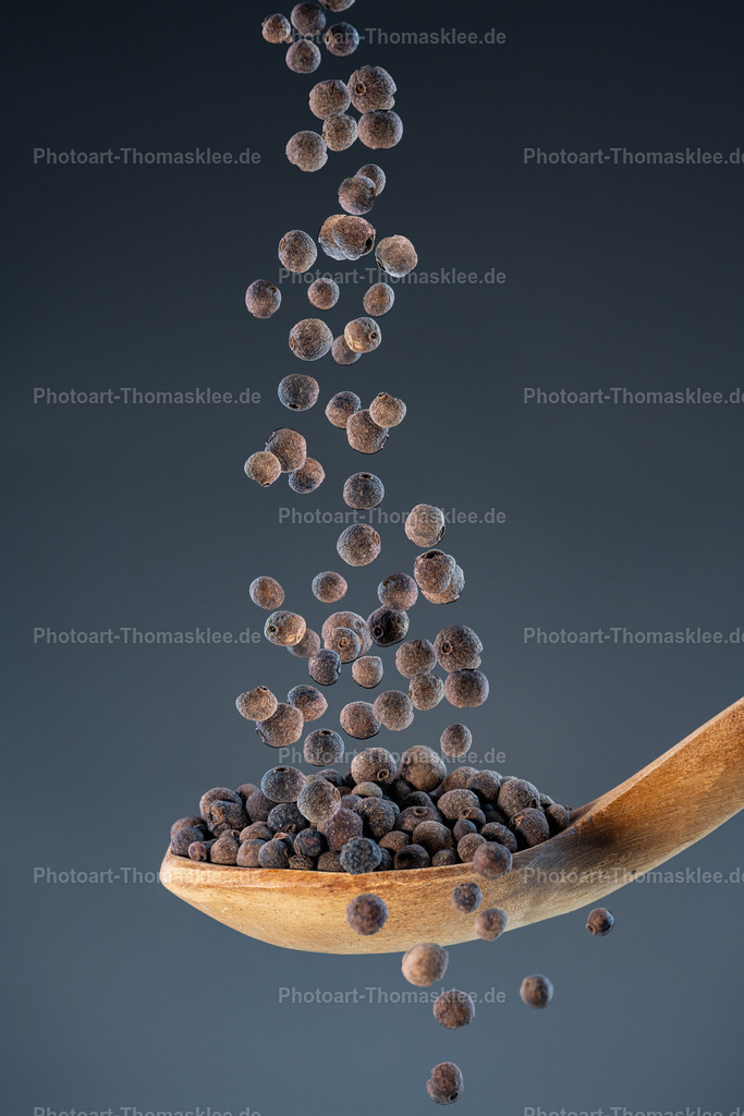 Piment – aromatische Vielseitigkeit | Piment – aromatische Vielseitigkeit. Kollektion: A spoon of tastefully seasonings.In dieser hochwertigen Studioaufnahme fallen zahlreiche große, runde Pimentkörner wie in Zeitlupe auf einen rustikalen Holzlöffel herab. Der Moment der Bewegung wird durch präzise Highspeed-Blitztechnik eingefroren und offenbart die feine Textur und das satte Braun der Pimentkörner. Der dunkle blaugraue Hintergrund setzt die natürlichen Farben und die organische Struktur der Gewürze kunstvoll in Szene. Das Bild vereint Dynamik, Natürlichkeit und eine elegante Schlichtheit und ist eine Hommage an die Vielfalt der Gewürzwelt. Perfekt geeignet für stilvolle Küchen, Delikatessläden oder Restaurants, die Wert auf eine warme und authentische Atmosphäre legen.Wo könnte man dieses Bild am besten aufhängen?Privater Bereich:In der Küche, um eine warme, naturverbundene Atmosphäre zu schaffen.Im Esszimmer über einem gedeckten Tisch für ein gemütliches, kulinarisches Ambiente.Gewerblicher Bereich:In einem Delikatessenladen oder Gewürzgeschäft als hochwertiges Highlight an der Wand.In gehobenen Restaurants, besonders solchen mit Fokus auf natürliche Zutaten und authentische Küche.Alu-Dibond: Die matte Oberfläche sorgt für eine edle, reflexionsfreie Präsentation der natürlichen Farben und der feinen Details der Pimentkörner.Acrylglas: Verstärkt die Tiefenwirkung der Körner und lässt die Farben noch intensiver und lebendiger erscheinen, perfekt für moderne Interieurs.Poster: Flexibel und leicht aufzuhängen – ideal für schnell wechselnde Dekorationen oder stilvolle Akzente in Küchen und Verkaufsräumen.Leinwand: Verleiht dem Motiv eine weiche, natürliche Wirkung, die wunderbar zum rustikalen Holzlöffel und den erdigen Tönen passt. - Realisiert mit Pictrs.com