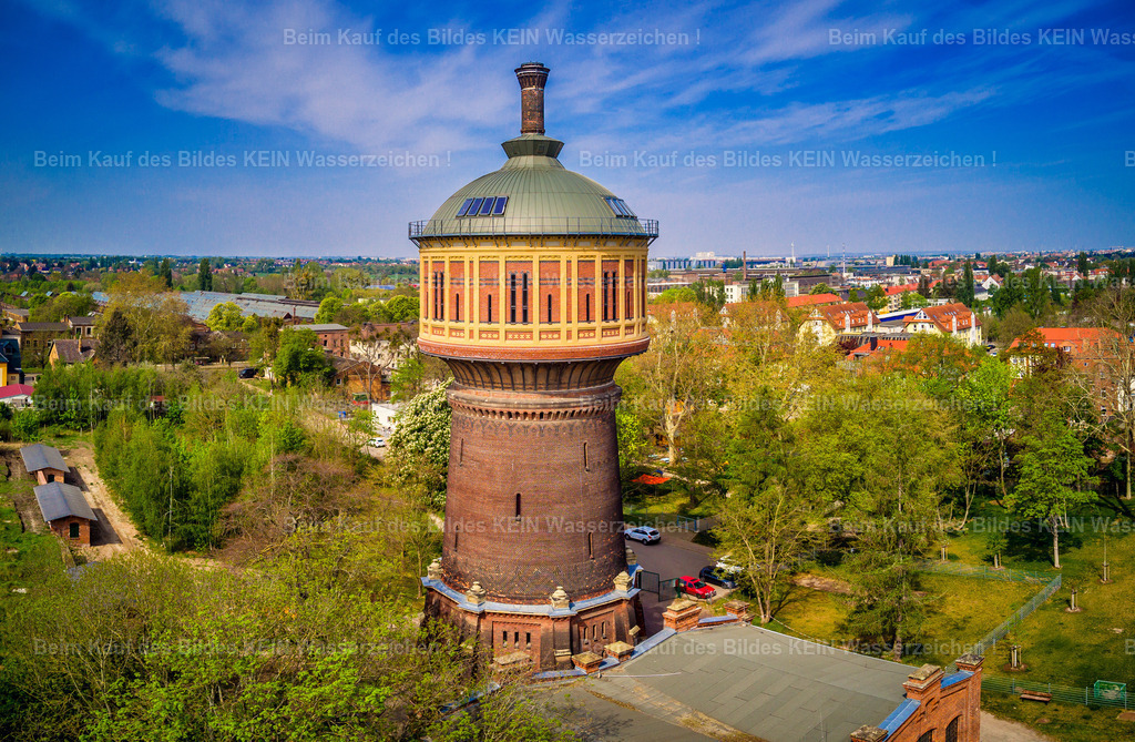 Wasserturm Salbke in Magdeburg von oben als Luftbild- | Diese Luftaufnahme zeigt den historischen Wasserturm im Magdeburger Stadtteil Salbke aus einer tiefen Drohnenperspektive. Vor einem strahlend blauen Himmel erhebt sich das markante Bauwerk über die umliegenden Baumkronen und wird von sattem Grün eingerahmt. Die niedrige Flughöhe rückt die eindrucksvolle Backsteinarchitektur und die charakteristische Form des denkmalgeschützten Wasserturms besonders wirkungsvoll in den Mittelpunkt. Als technisches Denkmal gehört er zu den markantesten Bauwerken im Süden Magdeburgs.Dieses Motiv zeigt beispielhaft die große Vielfalt der Architektur-Highlights, die für Ihren individuell gestalteten Luftbildkalender zur Verfügung stehen. Historische Wassertürme, denkmalgeschützte Gebäude, moderne Architektur oder markante Unternehmensstandorte – Sie entscheiden selbst, welche Motive Ihren Kalender prägen sollen. Alle gezeigten Luftaufnahmen verstehen sich als Vorschläge und können jederzeit durch andere Motive aus dem umfangreichen Luftbildarchiv ersetzt oder ergänzt werden.So entsteht ein hochwertiger Firmenkalender mit persönlichem und regionalem Bezug. Sie wählen Ihre Wunschmotive aus, ich übernehme die professionelle Gestaltung und Umsetzung. Die individuelle Motivauswahl gehört selbstverständlich zum Service und ermöglicht einen Kalender, der die architektonische Vielfalt Magdeburgs genau nach Ihren Vorstellungen präsentiert. - Realisiert mit Pictrs.com