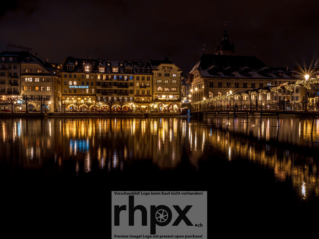 Goldene Winternacht Luzern | Nacht. Lichter. Reflexion.Luzern in ihrer stillsten und doch brillantesten Stunde. Die leuchtenden Fenster und die festlich beleuchtete Seebrücke spiegeln sich perfekt im ruhigen Wasser der Reuss. Es ist die Magie einer Winternacht, die die historische Altstadt in ein warmes, goldenes Licht taucht, fast so, als würde sie atmen.Wähle unter "Produktauswahl" dein Wunschformat: Vom klassischen Wandbild über Puzzle &amp; Tassen bis zum digitalen Download (z.B. als Handy-Hintergrund). - Realisiert mit Pictrs.com