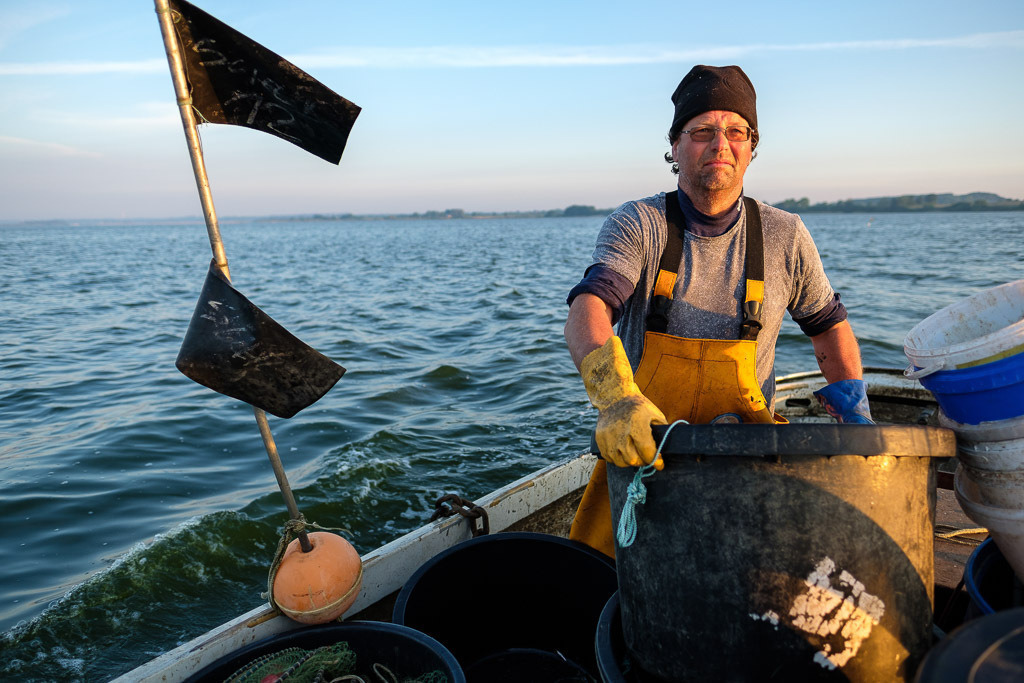 zeitenwende-farbe-03-07 | Matthias Nanz aus Schleswig ist einer der letzten Berufsfischer an der Schlei. Das Foto zeigt ihn auf seinem Boot frühmorgens Ende Mai 2019 beim Sortieren seiner Geräte auf der Fahrt zu den Fanggründen. - Realisiert mit Pictrs.com