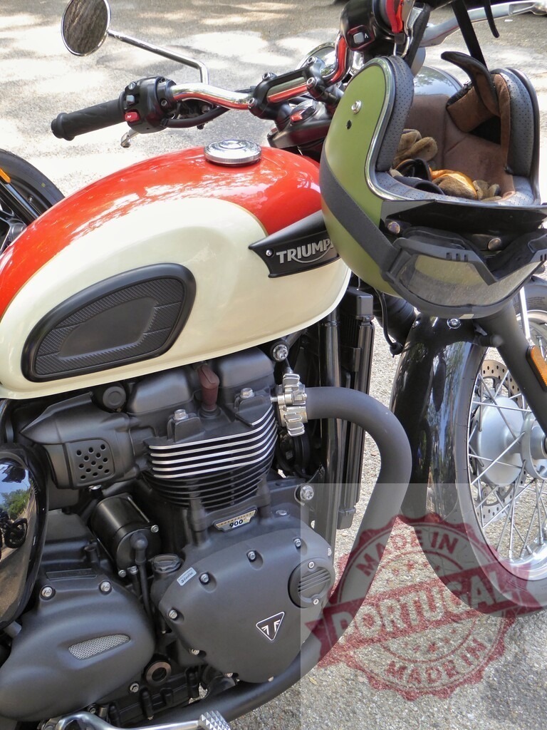 Triumph Motorcycle Parked on Asphalt with Helmet Hanging on Handlebar | Classic Triumph motorcycle parked on asphalt with a helmet and gloves hanging on the handlebar - Realisiert mit Pictrs.com