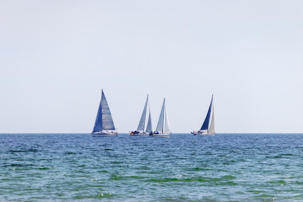Wandbild: Segelträume – Vier Boote auf der Ostsee | Sanfte Farben und eine beruhigende Küstenlandschaft – dieses Wandbild vermittelt die entspannte Atmosphäre eines Segeltages auf der Ostsee. Die vier Segelboote gleiten ruhig über das Wasser, während der weite Himmel für eine offene und harmonische Bildwirkung sorgt. - Realisiert mit Pictrs.com