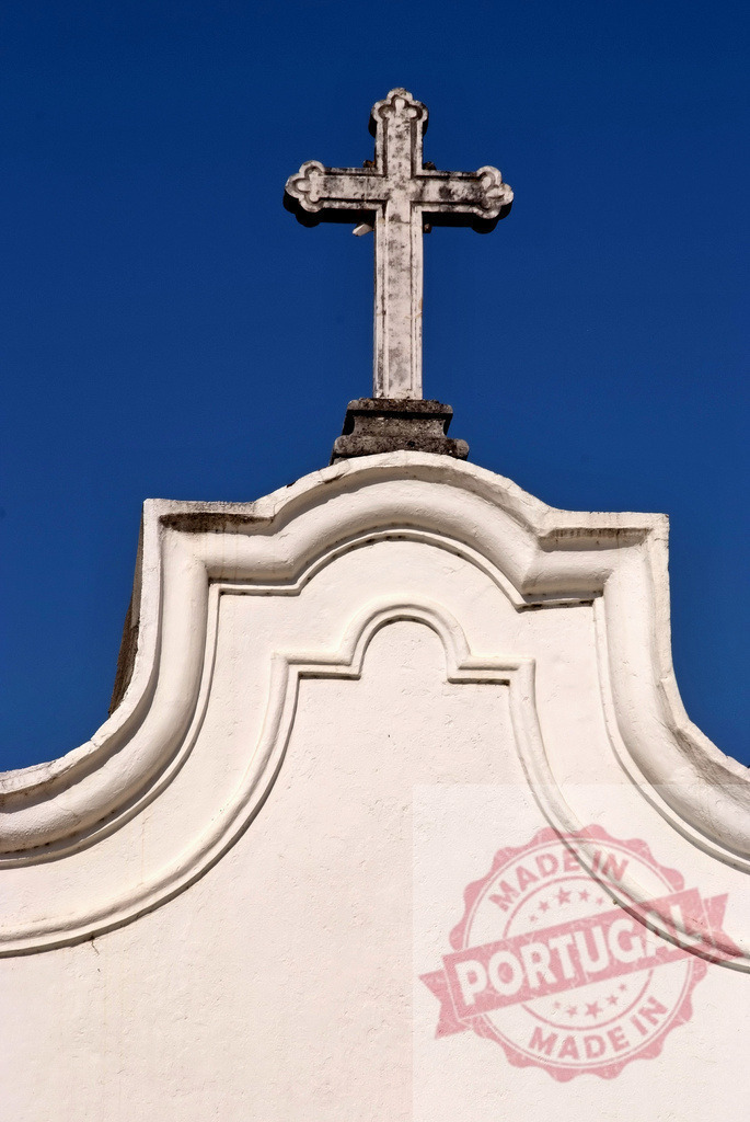 Cross on church facade against clear blue sky. Centro Portugal | Ornate christian cross topping a white church facade under a vivid blue sky - Realized with Pictrs.com