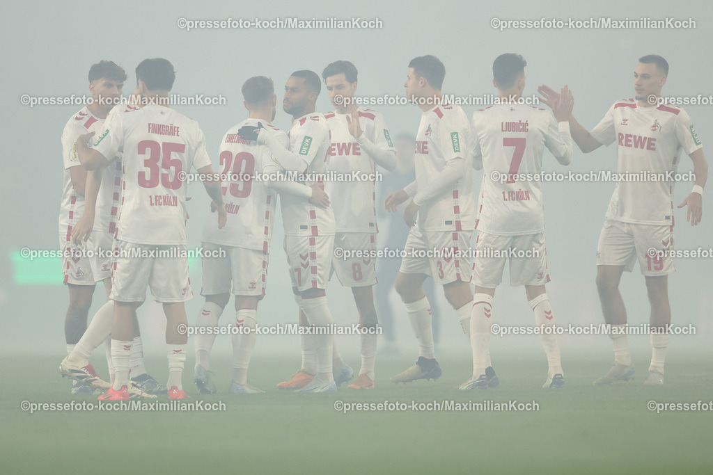 1FC04122403174 | 04.12.2024, Fußball, 1. FC Köln - Hertha BSC, Achtelfinale DFB-Pokal, RheinEnergieSTADION, Saison 2024 2025: Die Kölner stehen vor dem Spiel gemeinsam im Nebel auf dem Spielfeld. DFB regulations prohibit any use of photographs as image sequences and or quasi-video.