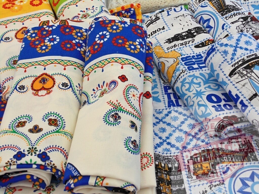 Portuguese textile souvenirs displaying traditional patterns and Porto icons | Colorful textiles featuring traditional Portuguese patterns and graphics of Porto landmarks - Realized with Pictrs.com