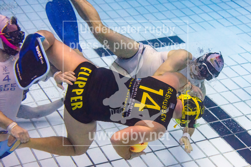 24. - 26.11.2023: Unterwasser-Rugby Champions Cup 2023  | Herren-Finale: Flippers (Dänemark) in blau gegen den DUC Krefeld (Deutschland) in weiß. Mikkel Rasmussen (blau #14) verteidigt geben zwei Krefelder Spieler den Ball. - Realisiert mit Pictrs.com