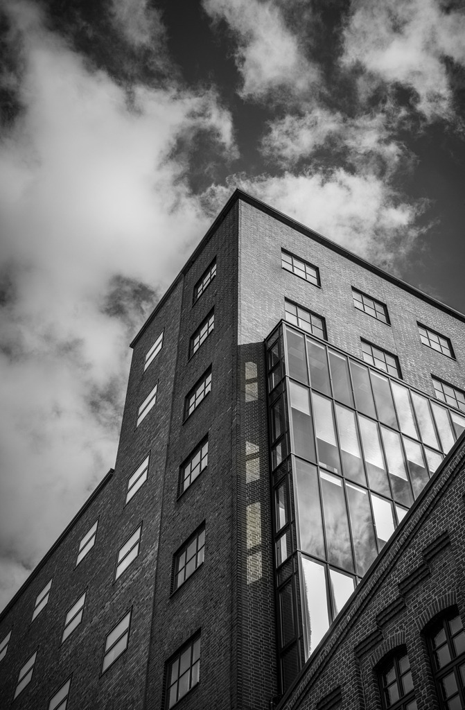Black and White Architecture Print, Urban Building Wall Art, Modern Fine Art Photography, Minimalist City Decor, Industrial Architecture | Bring a bold urban atmosphere into your space with this striking black and white architecture print.This fine art photograph captures the powerful contrast between industrial brick textures, reflective glass, and dramatic cloud formations from a strong upward perspective.Perfect for modern interiors, office spaces, loft apartments, and minimalist wall decor, this print adds depth, structure, and a contemporary architectural mood to any room.Ideal for lovers of:black and white wall arturban photographymodern architectureindustrial decorminimalist interiorsA timeless fine art print for modern spaces. - Realisiert mit Pictrs.com