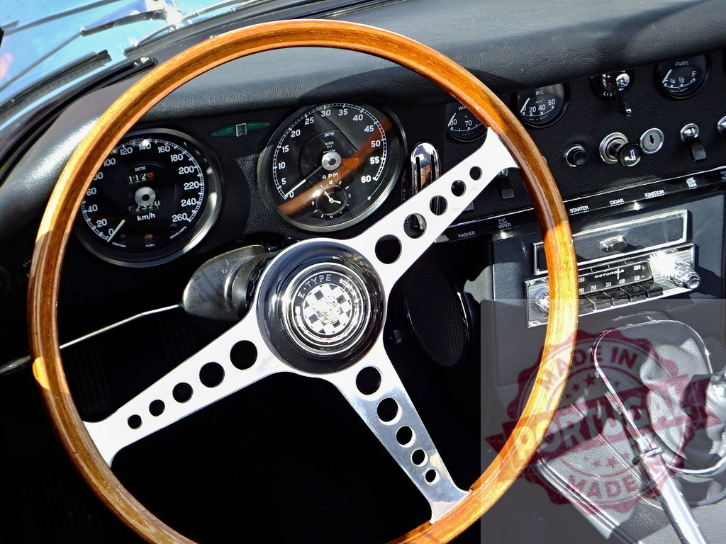 Wooden steering wheel and dashboard of a classic Jaguar E-Type sports car | Close-up of the wooden steering wheel and dashboard instruments of a vintage Jaguar E-Type, showcasing its classic design - Realisiert mit Pictrs.com