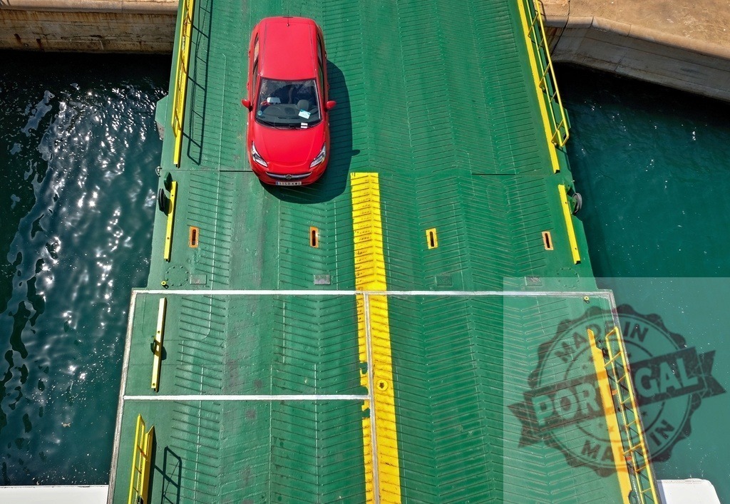 Red car driving onto car ferry connecting land | Red vehicle driving onto a green car ferry with clear blue water below, seen from above - Realized with Pictrs.com