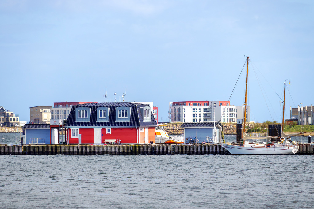 Wandbild: Yachthafen in Olpenitz | Dieses Wandbild im Querformat zeigt den Yachthafen in Olpenitz. Im Hintergrund sind die Ferienwohnungen zu sehen. Der Himmel ist blau.  - Realisiert mit Pictrs.com