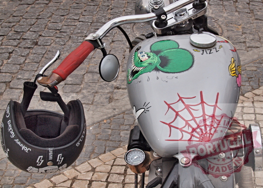 Custom motorcycle fuel tank with Rat Fink sticker | Close up view of a custom motorcycle fuel tank featuring a Rat Fink graphic and spiderweb design - Realisiert mit Pictrs.com