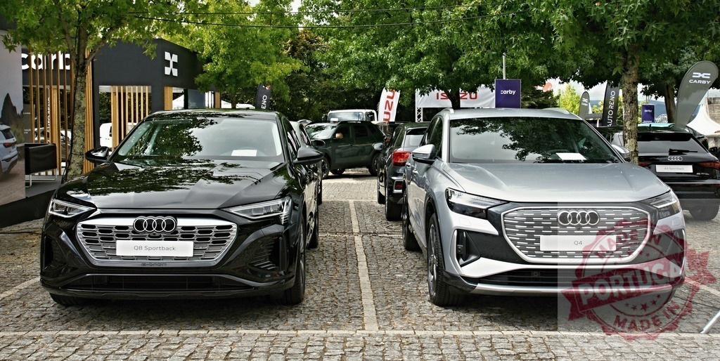 Audi Q8 Sportback and Q4 e-tron at automobile exhibition | Two electric Audi SUVs, the Q8 Sportback and Q4 e-tron, displayed at an outdoor car show - Realized with Pictrs.com