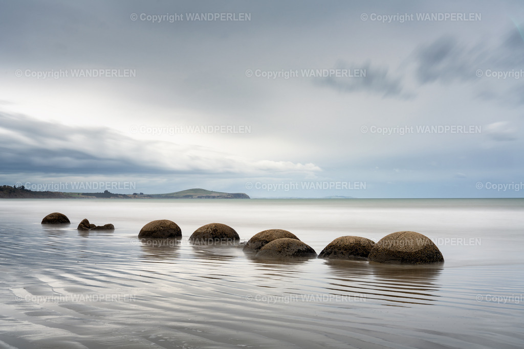 November - Moeraki Boulders im Herbst | Herbst am Strand der Moeraki Boulders – eine Reihe massiver, kugelförmiger Felsen ruht im ruhigen, flachen Wasser unter einem sanften, bewölkten Himmel. Die friedliche Landschaft vermittelt ein Gefühl zeitloser Schönheit und natürlicher Wunder. - Realisiert mit Pictrs.com