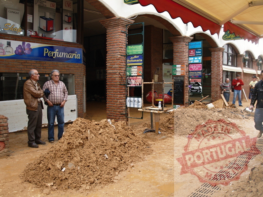 Community dealing with flood mud aftermath cleanup | Albufeira Flood - discruction by weather problems People and shops facing the challenging aftermath of a natural disaster, cleaning up mud from a flood - Realisiert mit Pictrs.com