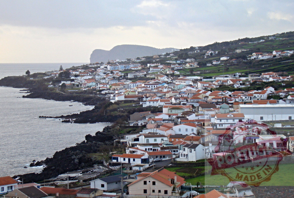 Coastal town on São Miguel island, Azores, Portugal | Coastal town houses dotting the volcanic coastline with green fields and distant hills - Realized with Pictrs.com
