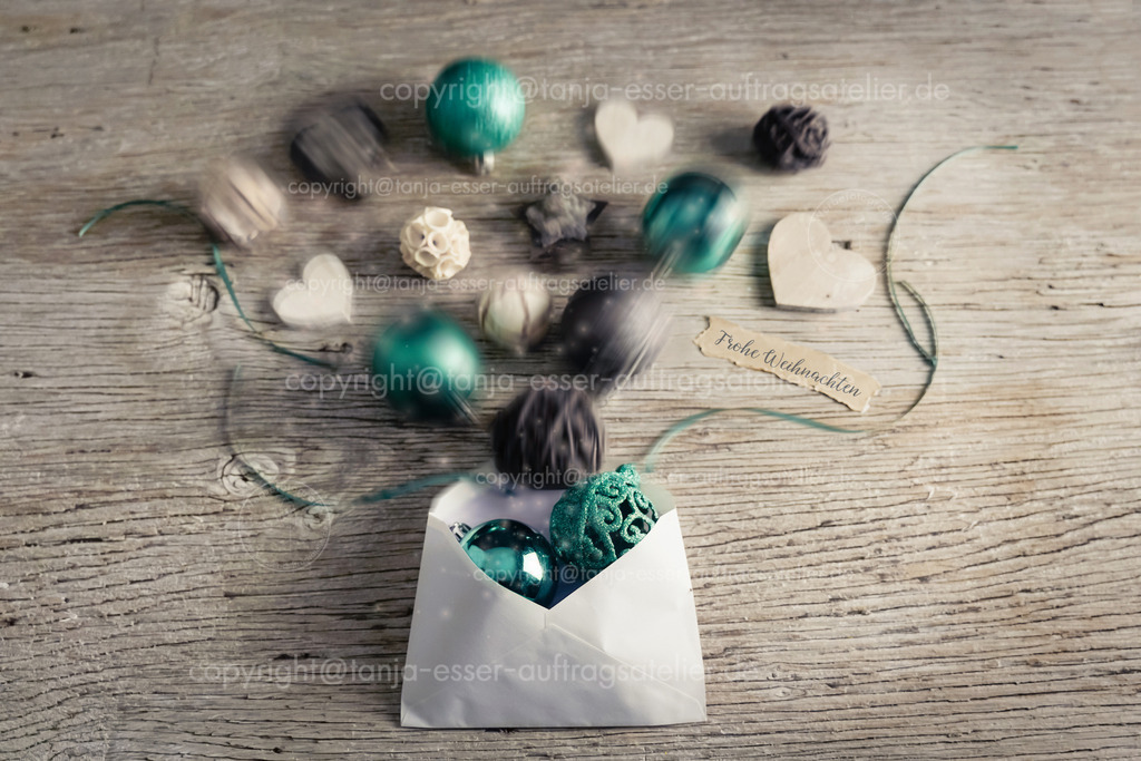 Weihnachtsbild in kühlen dezenten Farben zeigt einen Weihnachts-Briefumschlag, aus dem Weihnachtskugeln heraus springen und deutscher Text: Frohe Weihnachten.  |   Türkis und Beige spielen die Hauptrolle auf diesem dekorativen Weihnachtsmotiv. Die Bewegung wird durch Unschärfe dargestellt. Frisch und fröhlich.                             