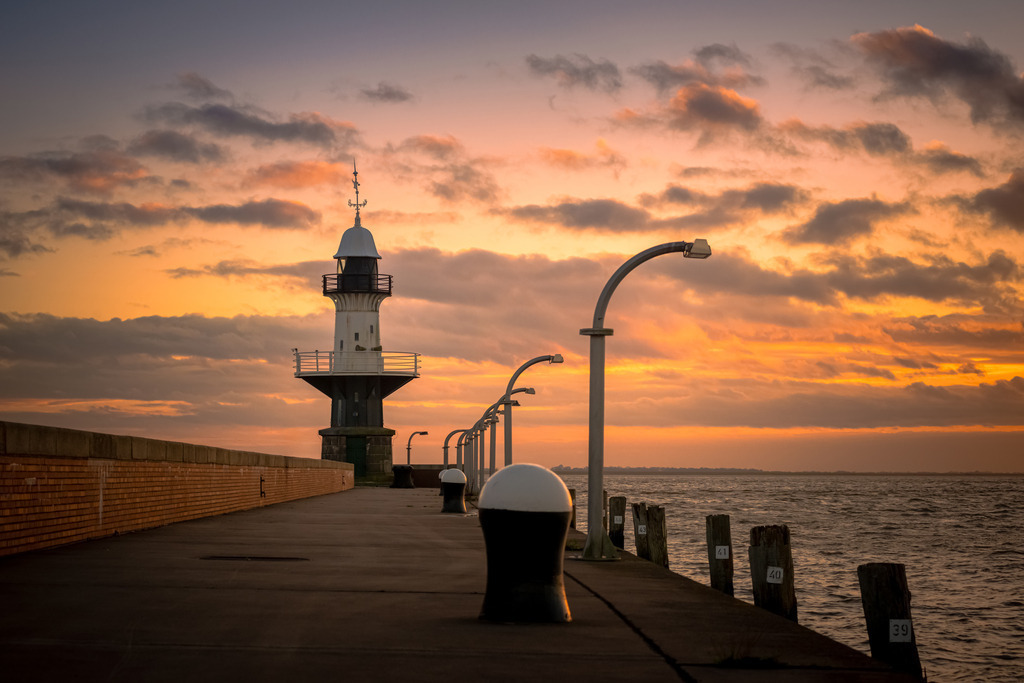 Leuchtturm "Mole 1" Brunsbüttel | Der historische Leuchtturm "Mole 1" in Brunsbüttel präsentiert sich majestätisch vor dem beeindruckenden Hintergrund eines malerischen Sonnenuntergangs. In diesem idyllischen Szenario wird der Leuchtturm "Mole 1" zu einem zeitlosen Symbol der Schifffahrtsgeschichte, das in der malerischen Kulisse eines Sonnenuntergangs seinen ganz eigenen Charme entfaltet.