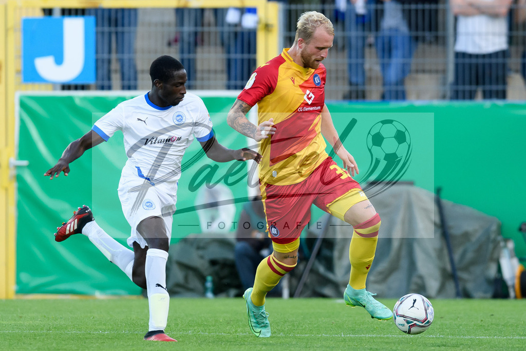 LOTKSC20210809_231 | Fussball, Herren: Philipp Hofmann (Karlsruher SC) und Komlan Fionouke (Sportfreunde Lotte) im Zweikampf beim Spiel der 1. Runde im DFB-Pokal zwischen SF Lotte und Karlsruher SC im Stadion am Lotter Kreuz am 09.08.2021 in Lotte, Deutschland.DFB / DFL REGULATIONS PROHIBIT ANY USE OF PHOTOGRAPHS AS IMAGE SEQUENCES AND/OR QUASI-VIDEO. - Realisiert mit Pictrs.com