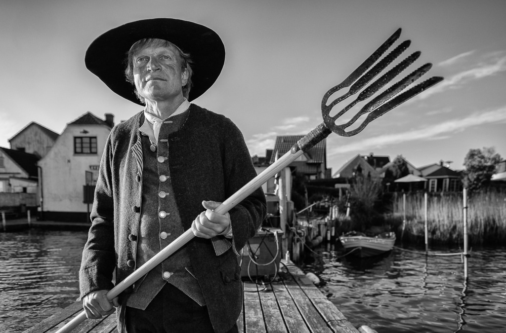 fischer-2020-089 | Jörg Nadler ist Mitglied der Holmer Fischerzunft in Schleswig. Er nennt sich "historischer Fischer", weil er neben seinem Hauptberuf das Fischerhandwerk früherer Epochen als Darsteller u. a. bei museumspädagogischen Veranstaltungen lebendig vermittelt. Hier ist er als Fischer der Barockzeit auf seiner Brücke am Ufer des Holms zu sehen. - Realisiert mit Pictrs.com