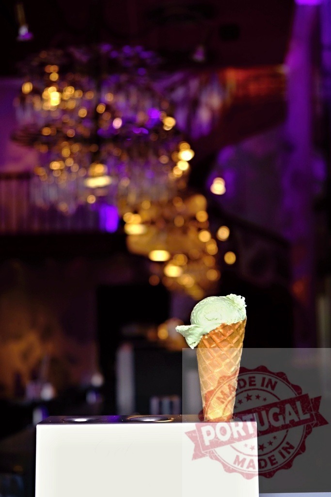 Pistachio ice cream scoop in waffle cone at restaurant | Pistachio ice cream scoop standing in a waffle cone against a bokeh background - Realized with Pictrs.com