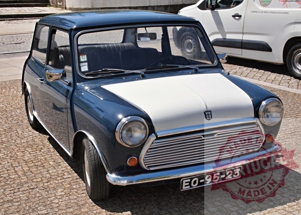 Mini Cooper classic driving on cobblestone street | Blue and white Mini Cooper car parked on a European city street on a sunny day - Realized with Pictrs.com