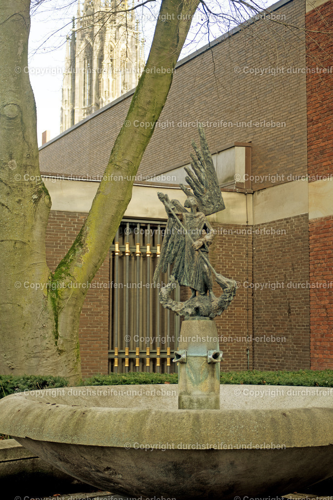 St.-Michaels-Brunnen mit Himmelsleiter der Lambertikirche Münster | Zu sehen ist der St.-Michaels-Brunnen. Gezeigt wird, wie der Heilige auf einem Drachen steht. Im Hintergrund  die Himmelsleiter an einem Turm der Lambertikirche Münster. - Realisiert mit Pictrs.com
