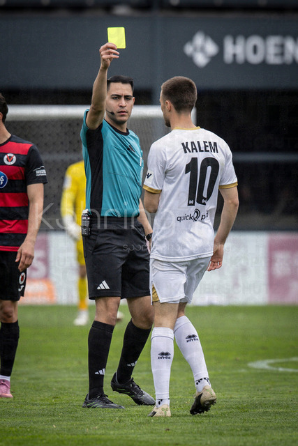 Viktoria Koeln vs. SV Wehen Wiesbaden, 11.04.2026 | KOELN, GERMANY - APRIL 11, 2026:  referee Cengiz Kabalakli (Gelsenkirchen) shows Robin Kalem (SV Wehen Wiesbaden, 10) the yellow card after a foul during the 3rd division match between Viktoria Koeln vs. SV Wehen Wiesbaden at the Sportpark Hoehenberg on matchday 7 on April 11, 2026 in Koeln, Germany. DFL REGULATIONS PROHIBIT ANY USE OF PHOTOGRAPHS AS IMAGE SEQUENCES AND/OR QUASI-VIDEO.