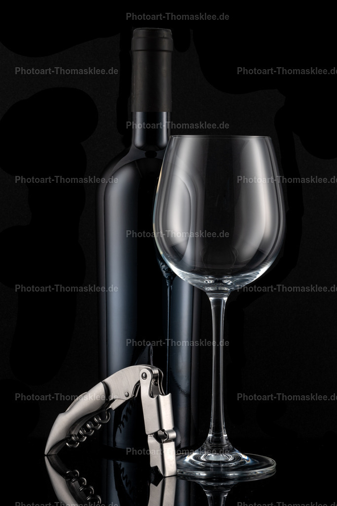 Minimalistisches Wein Stillleben - Flasche, Glas, Öffner | Diese minimalistische Weinkomposition zeigt eine elegante dunkle Flasche neben einem leeren Weinglas und einem modernen Korkenzieher vor schwarzem Hintergrund. Die monochromatische Farbgebung verstärkt die edle Ausstrahlung und lenkt den Fokus auf die klassischen Formen. Der silberne Korkenzieher mit seinem geschwungenen Design bildet einen schönen Kontrast zur geradlinigen Flasche. Subtile Lichtreflexe auf den glatten Oberflächen schaffen Tiefe und Dramatik. Ein zeitloses Motiv für stilvolle Weinliebhaber. - Realisiert mit Pictrs.com