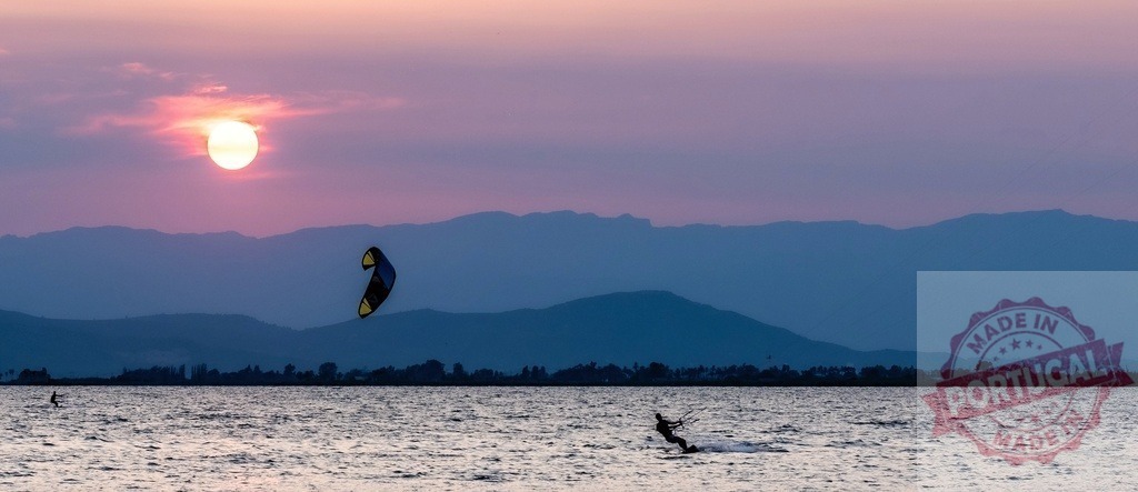 Kiteboarder riding at sunset with mountains horizon | Silhouette of a kiteboarder on water during a colorful sunset over mountains - Realisiert mit Pictrs.com