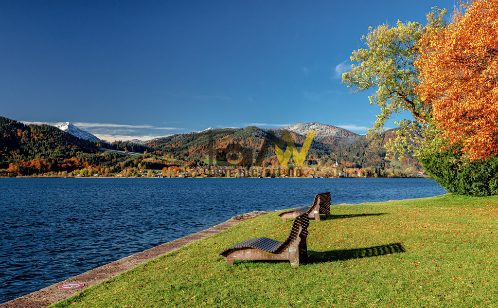 Idyllischer herbstlicher Blick über den Tegernsee | Das Bild zeigt den Tegernsee in Bayern, Deutschland, während der Herbstsaison. Der Tegernsee ist ein beliebter Alpensee, umgeben von den bayerischen Alpen. Die Region ist bekannt für ihre malerische Landschaft, die im Herbst durch leuchtende Farben und oft schneebedeckte Berggipfel im Hintergrund gekennzeichnet ist. Der Wallberg in Rottach-Egern ist der Hausberg der Region und thront mit 1722 m über dem See. Die Gegend bietet zahlreiche Aktivitäten wie Wandern, Radfahren, Bootsfahrten und Wintersportmöglichkeiten in der kälteren Jahreszeit.  - Realisiert mit Pictrs.com