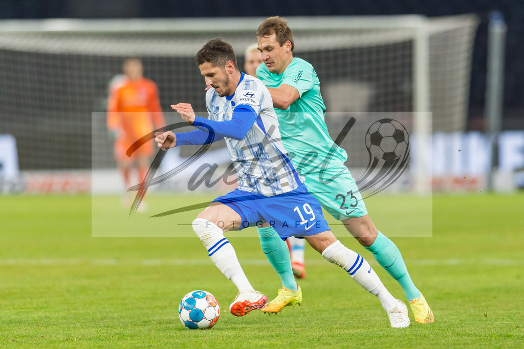 HERBOC20220204_010 | Fussball, Herren: Robert Tesche (VfL Bochum) und Stevan Jovetic (Hertha BSC) im Zweikampf bei dem Spiel der 1. Bundesliga zwischen Hertha BSC und VfL Bochum im Olypiastadion am 04.02.2022 in Berlin, Deutschland.DFB / DFL REGULATIONS PROHIBIT ANY USE OF PHOTOGRAPHS AS IMAGE SEQUENCES AND/OR QUASI-VIDEO. - Realisiert mit Pictrs.com