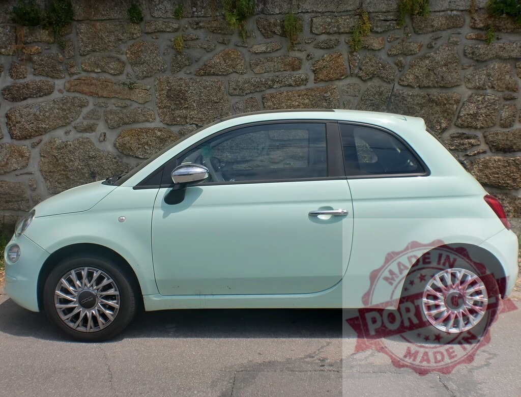 Fiat 500 driving city car on urban road | Fiat 500 driving on an urban paved road next to a stone wall - Realized with Pictrs.com