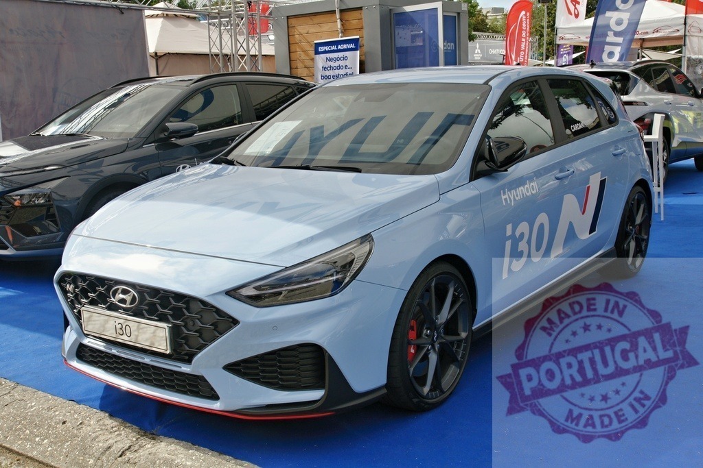 Hyundai i30 N performance hatchback at auto show | Light blue Hyundai i30 N compact car standing on blue carpet at an automotive event - Realized with Pictrs.com