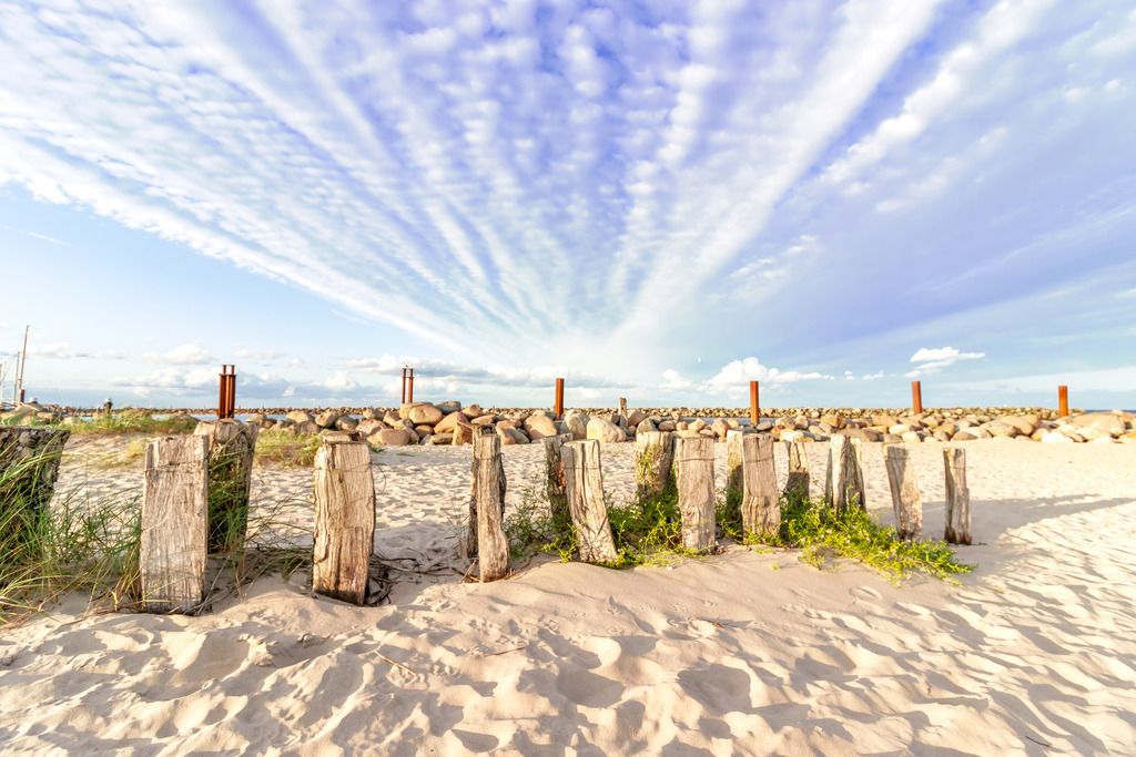 Leinwand: Nordische Weite – Küstenlandschaft mit Wolkenfächer | Die beruhigende Kraft der Küstenlandschaft – dieses Wandbild zeigt die natürliche Schönheit des Strandes mit feinem Sand, einem sanften Sandfang und einer Steinmole im Hintergrund. Die markante Wolkenformation am Himmel fächert sich über dem Horizont auf und schafft eine offene, entspannte Bildwirkung. Das Zusammenspiel von Himmel, Meer und Strand vermittelt Ruhe, Weite und die klare Ästhetik norddeutscher Küstenlandschaften. Ideal für Räume, die Natürlichkeit und Gelassenheit ausstrahlen sollen. Maritime Klarheit für Ihre Wände – dieses Leinwandbild bringt Struktur, Ruhe und nordische Eleganz in Ihre Räume. - Realisiert mit Pictrs.com